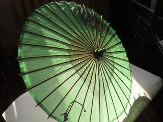 Old green sunshade with wooden ribs and pole
