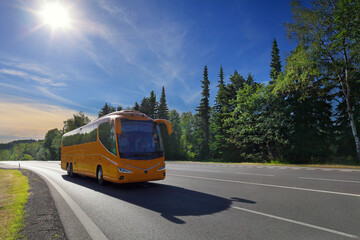 Obraz premium Yellow bus on the road at sunset carrying tourists on vacation