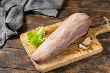Beef tongue on a wooden Board on a brown wooden table. Raw beef tongue on the kitchen table. Rustic style