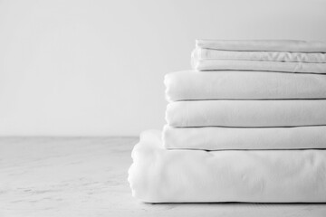 Stack of clean bed sheets on table - obrazy, fototapety, plakaty