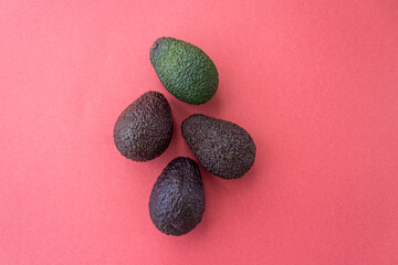 Avocado in different degrees of ripeness on a red background. Flat lay style. Close up. Place for text