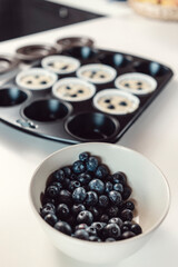Bowl of blueberries and tray of raw muffins before baking