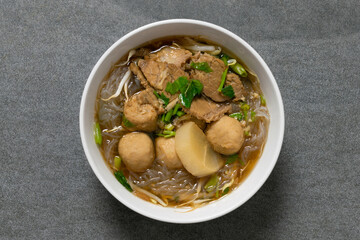 Vermicelli with beef in white bowl on concrete table.