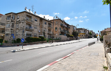 nearly empty street in Nakhalat Tsiyon in jerusalem israel during the corona virus covid pandemic lockdown with a clear sky and a few clouds in the background