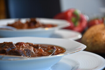 Beef Stew mexican style - with kidneybeans Paprika and tomatoes on a white plate served on a dark table - close up
