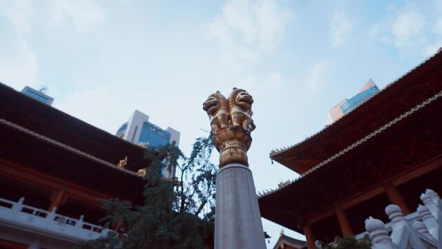 Jing'an Temple in Shanghai. Panning view of lions statue in Buddhist temple with focus on the rooftop architecture. Skyline in the background