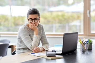 remote job, technology and people concept - bored or tired young woman in glasses with laptop computer working at home office