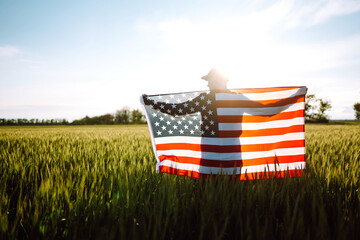 Fourth of July. Patriotic man with the national American flag in the field. Young man proudly waving an American flag. Independence Day. 