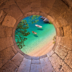 Hiden beach in Brela with boats on emerald sea aerial view through stone window