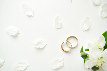 Fototapeta na wymiar Wedding ring. On a white background and with delicate white flowers. Wedding symbols and attributes