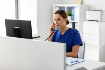 medicine, technology and healthcare concept - female doctor or nurse with computer calling on phone at hospital