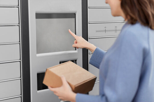 mail delivery and post service concept - close up of happy smiling woman with box at outdoor automated parcel machine choosing operation on touch screen