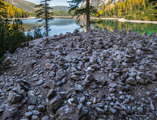 Small stone pyramides near autumn peaceful alpine lake Braies or Pragser Wildsee, South Tyrol, Dolomites Alps, Italy. Picturesque traveling, seasonal and nature beauty concept scene.