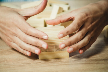 girl stacks a tower of wooden bricks at the table close-up