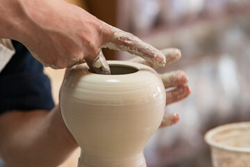 Potter sculpts from clay in a workshop of pots using ancient technology.