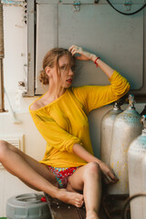 Girl with long hair in a yellow sports turtleneck poses on a fishing boat at sea