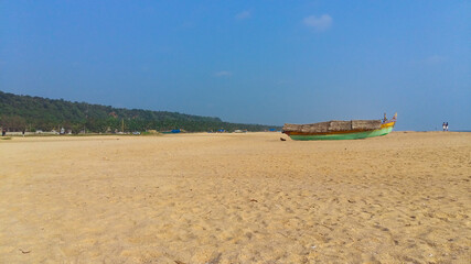 Landscape image of sandy Azhimala Beach in Trivandrum, Kerala, India with a parked fishing Boat on sand.