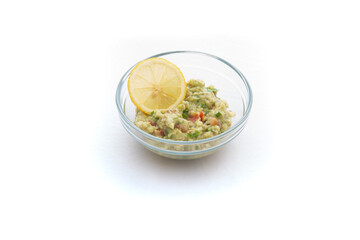 Homemade Guacamole in a glass bowl. Healthy breakfast with lemon. Isolated on white.