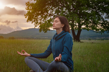 A young woman doing yoga in the field.