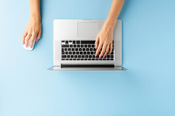 Fototapeta na wymiar Overhead shot of female hands using laptop on blue office desktop. Business background. Flat lay