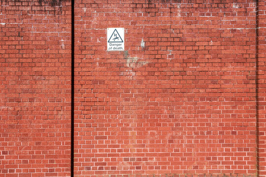 Red brick wall with a warning sign of high voltage danger