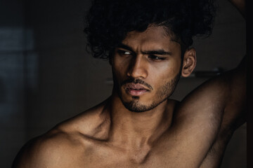Portrait close up of a handsome Indian or Arab male model with light brown skin and black curly hair