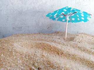 Papierschirmchen türkis auf Sand