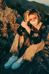 Fototapeta premium Blonde masked girl enjoying the sunset during the pandemic.