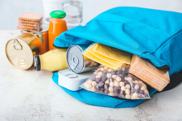 Schoolbag with different products on light background. Concept of Backpack Food Program