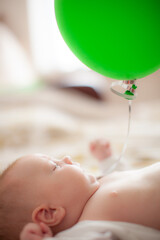 infant with green baloon laying