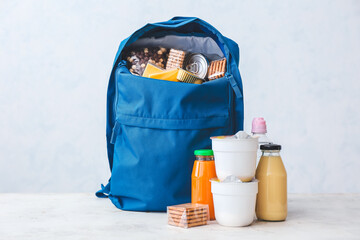 Schoolbag with different products on light background. Concept of Backpack Food Program