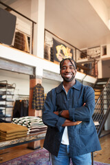 Portrait Of Smiling Male Owner Of Fashion Store Standing In Front Of Clothing Display