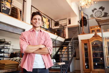 Portrait Of Smiling Male Owner Of Fashion Store Standing In Front Of Clothing Display