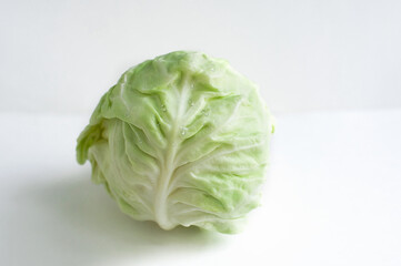 Fresh white cabbage with water drops on a light background. Healthy food, proper nutrition