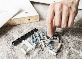 Hand choosing screw. Man assembling new furniture for home concept