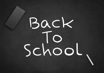 Fototapeta na wymiar Back to school written on black chalkboard with wiper and white chalk