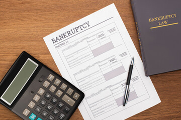 top view of bankruptcy paper, law book and calculator on wooden background