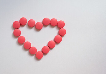The pink tablets are arranged in the shape of a heart. Vitamins for the heart.