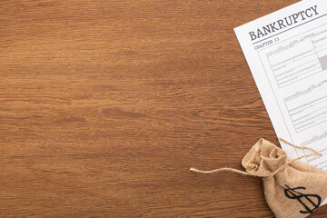 top view of money bag, bankruptcy paper on wooden background