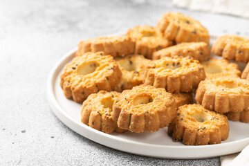 Shortbread in a white ceramic plate on a light table. A plate of cookies on the gray kitchen table. Cookies close up