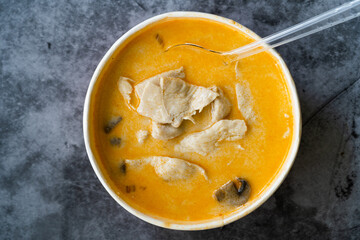 Take Away Thai Style Tom Kha Gai Soup with Coconut Milk, Chicken and Galangal in Plastic Bowl Package / Container.