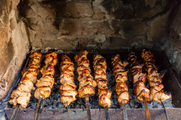 Process grilled kebab cooking in brick stove. Roasted meat cooked at barbecue. Summer BBQ fresh chicken meat chop cubes. Grill on charcoal and flame. Picnic and street food. Close up nature picnic