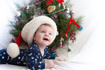 infant in santa hat near christmas tree new year