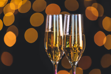 Glasses of tasty champagne on dark background with blurred lights