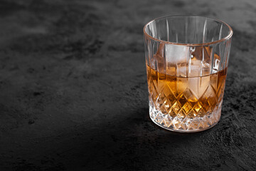 Glass with whiskey or rom with ice cubes on concrete background.. Copy space. 