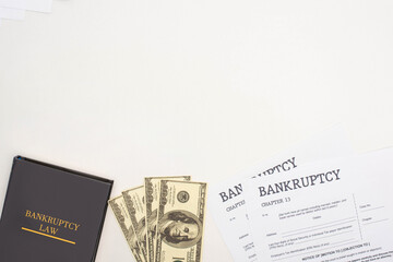 top view of bankruptcy papers, law book and money on white background