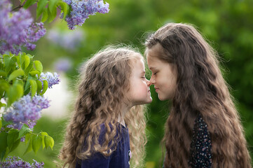 Outside is a portrait of two sisters among the lilac bushes.