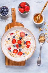 Healthy breakfast, bowl with oat granola, milk and berries.