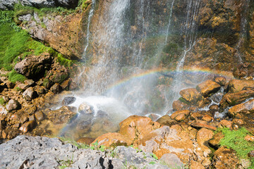 waterfall with small rainbow and brown rocks, austrian alps