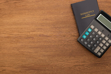 top view of bankruptcy law book and calculator on wooden background